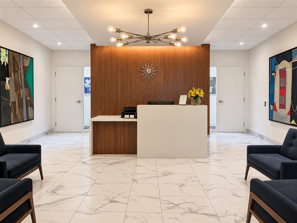 The reception area, with a walnut feature wall, a marble floor, and navy armchairs